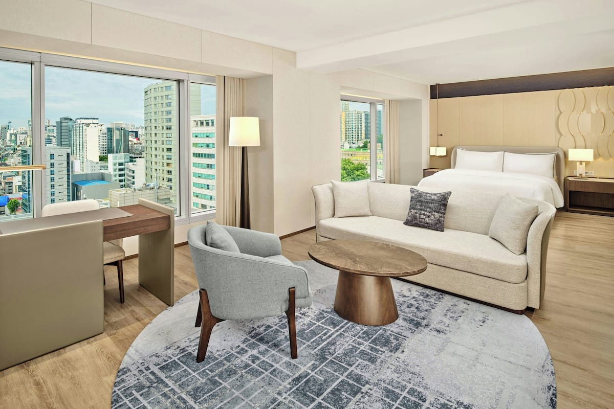 Une chambre d’hôtel moderne avec vue sur la ville, comprenant un canapé, une table basse ronde et un lit.