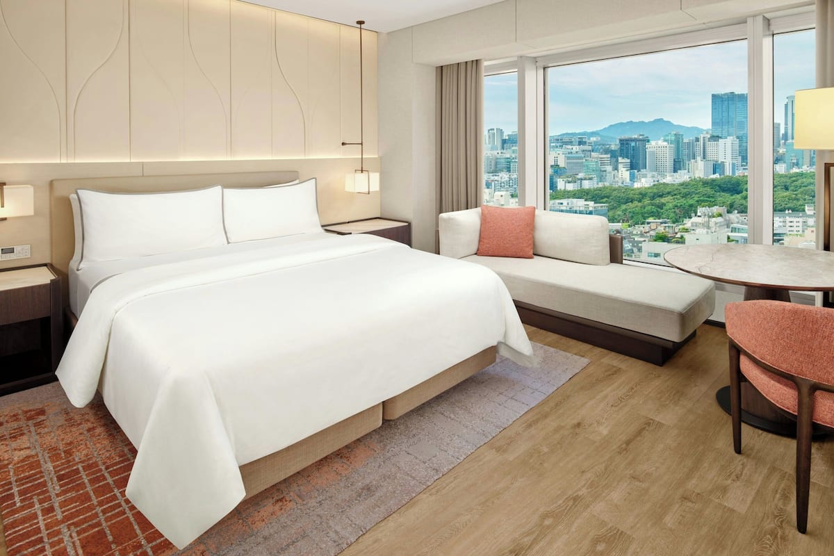 Une chambre d’hôtel avec un lit, un canapé, une petite table et une chaise.
