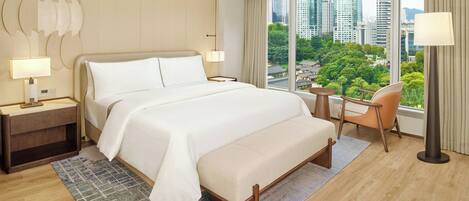 Quarto de hotel com uma cama grande, uma escrivaninha, uma cadeira e vista para a cidade.
