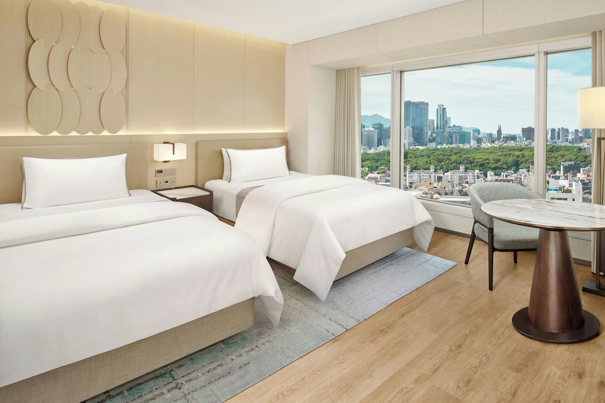 Une chambre d’hôtel avec deux lits, une table à manger et une vue sur la ville.