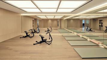 A spacious gym with multiple exercise bikes and mats, large windows, and a modern design.