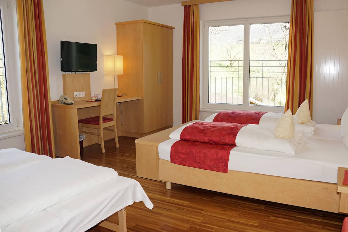 Een hotelkamer met een bed, bureau, stoel, televisie en een raam met gordijnen.