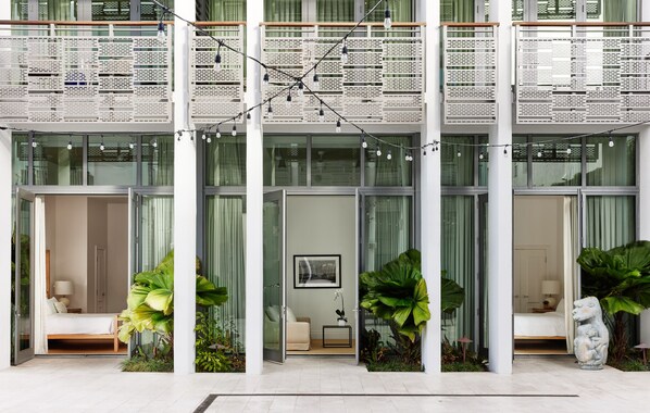 Un hotel moderno con un vestíbulo amplio, ventanas grandes y un balcón decorado con luces colgantes.