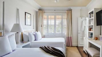 Une chambre d’hôtel avec deux lits, un bureau, une bibliothèque et une fenêtre avec des rideaux.
