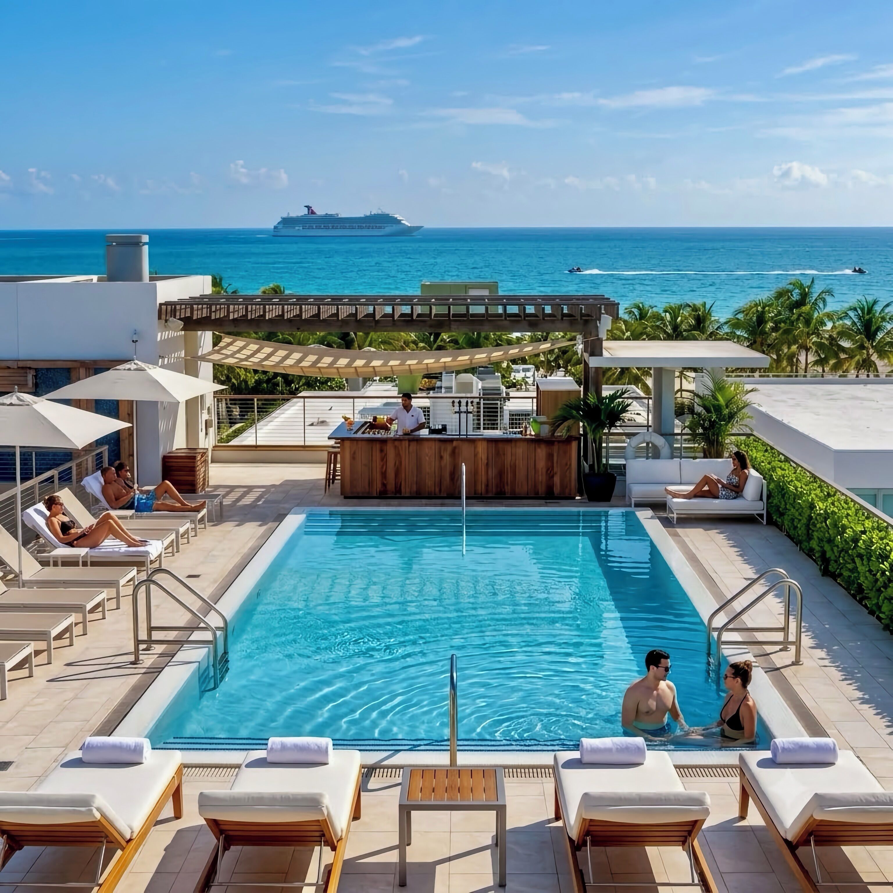 Uma área de piscina com espreguiçadeiras, bar e vista para o oceano.
