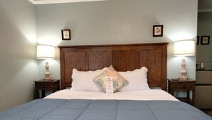 Un lit bien fait, avec une couette bleue, deux lampes de chevet et une tête de lit en bois.