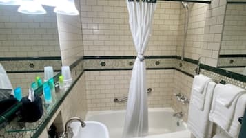 A bathroom with a bathtub, a sink, and a toilet. There are toiletries on the counter.