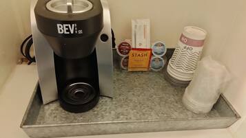 Une machine à café, une boîte étiquetée « STASH », et une pile d’assiettes sur un plateau.
