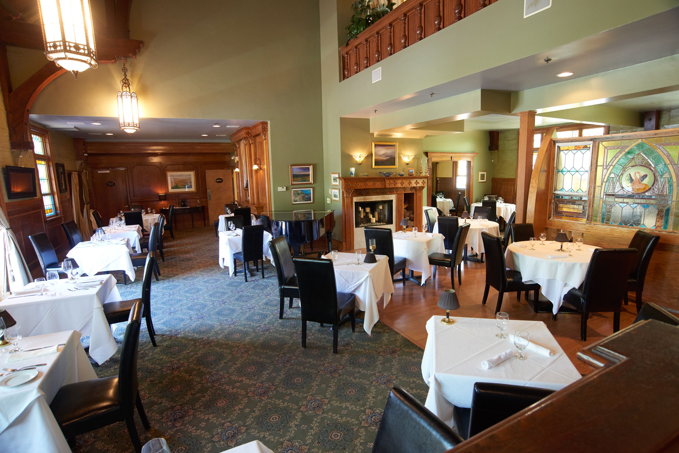 A dining area with multiple tables and chairs, a fireplace, and framed artwork on the walls.