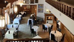 A dining area with multiple tables and chairs, wooden beams on the ceiling, and framed artwork on the walls. - Belfry Inn & Bistro (Sandwich)