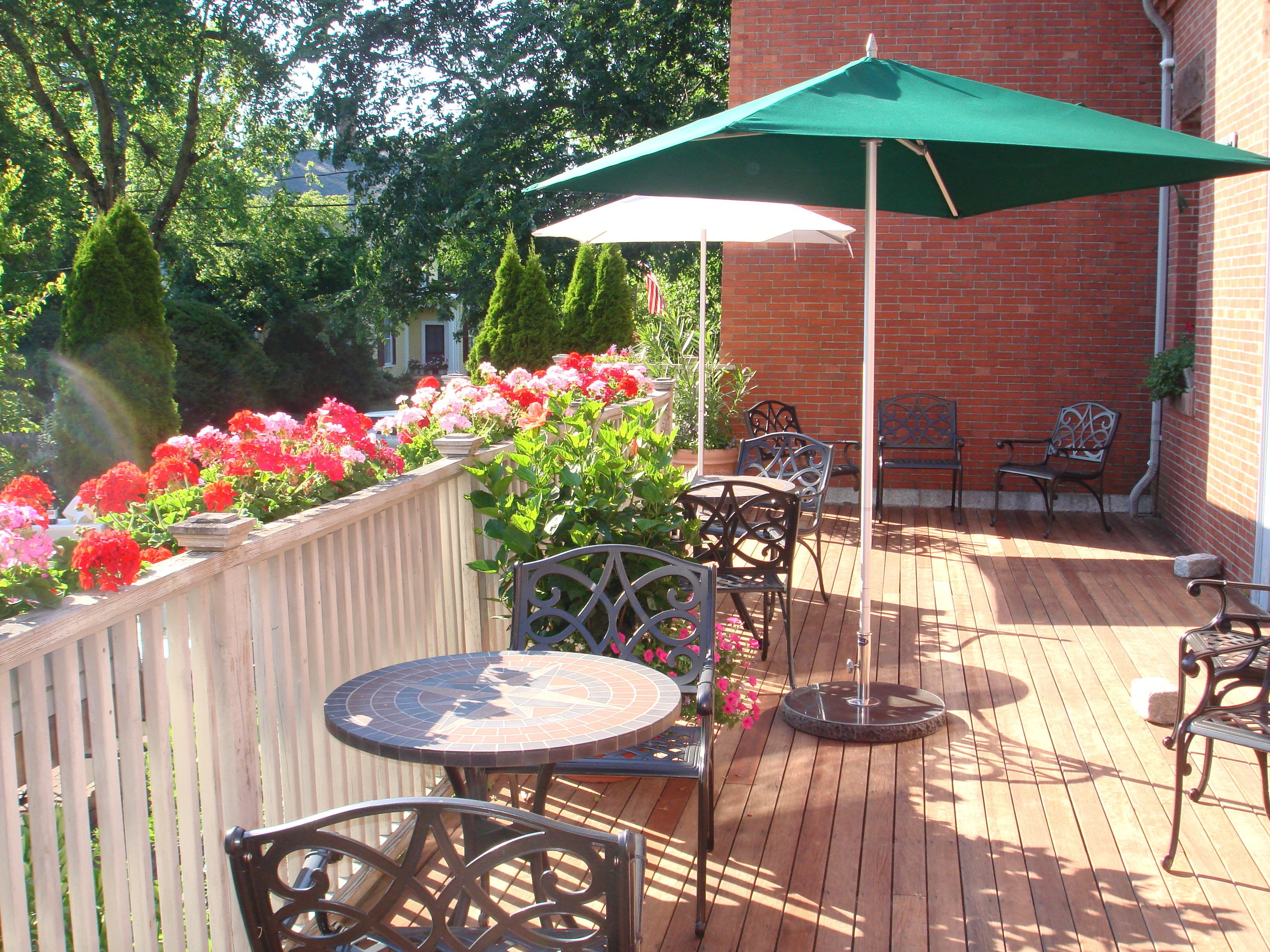 A patio with a round table and chairs, a green umbrella, and a brick wall.