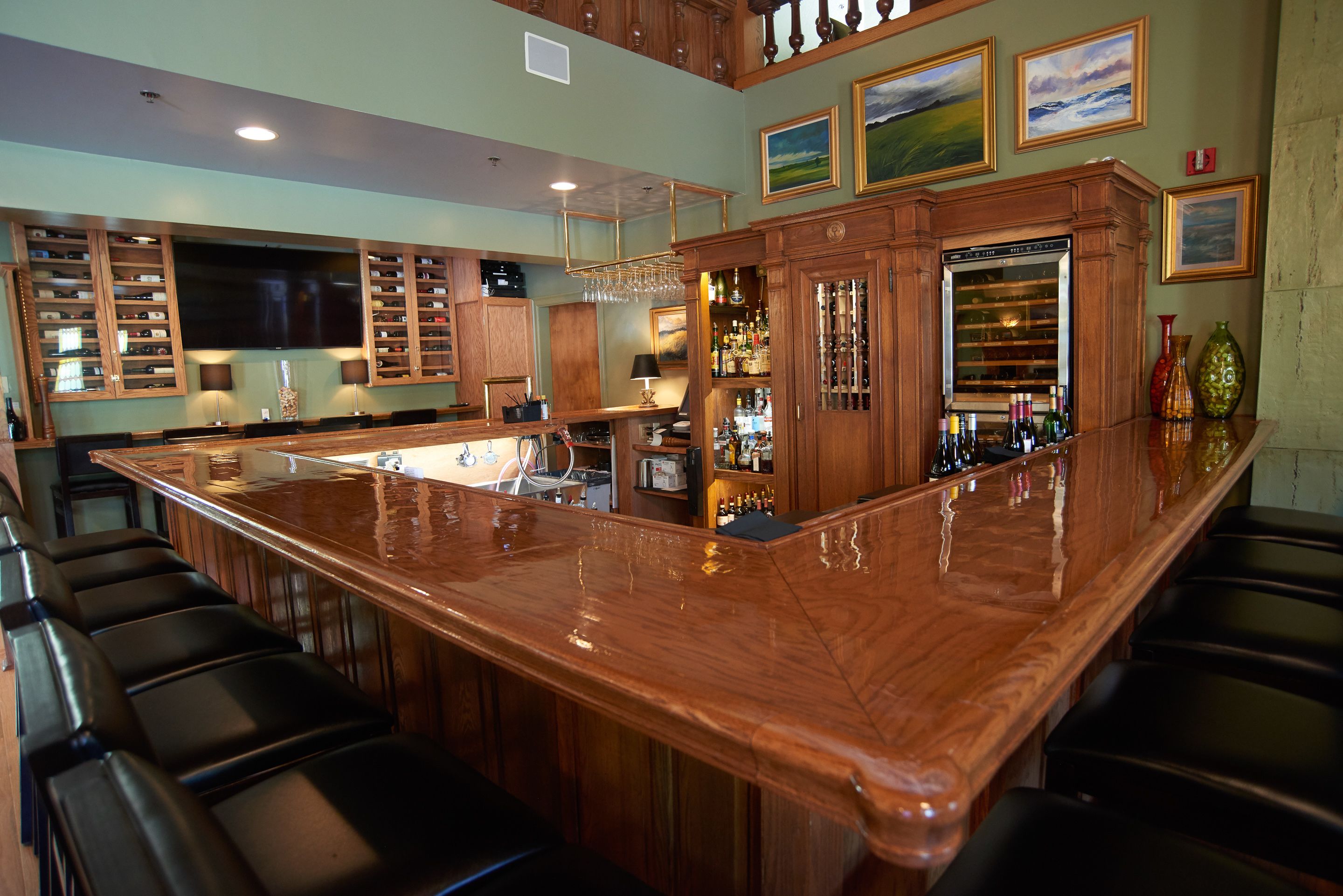 A bar area with a long counter, multiple seating options, and a television mounted above the bar.