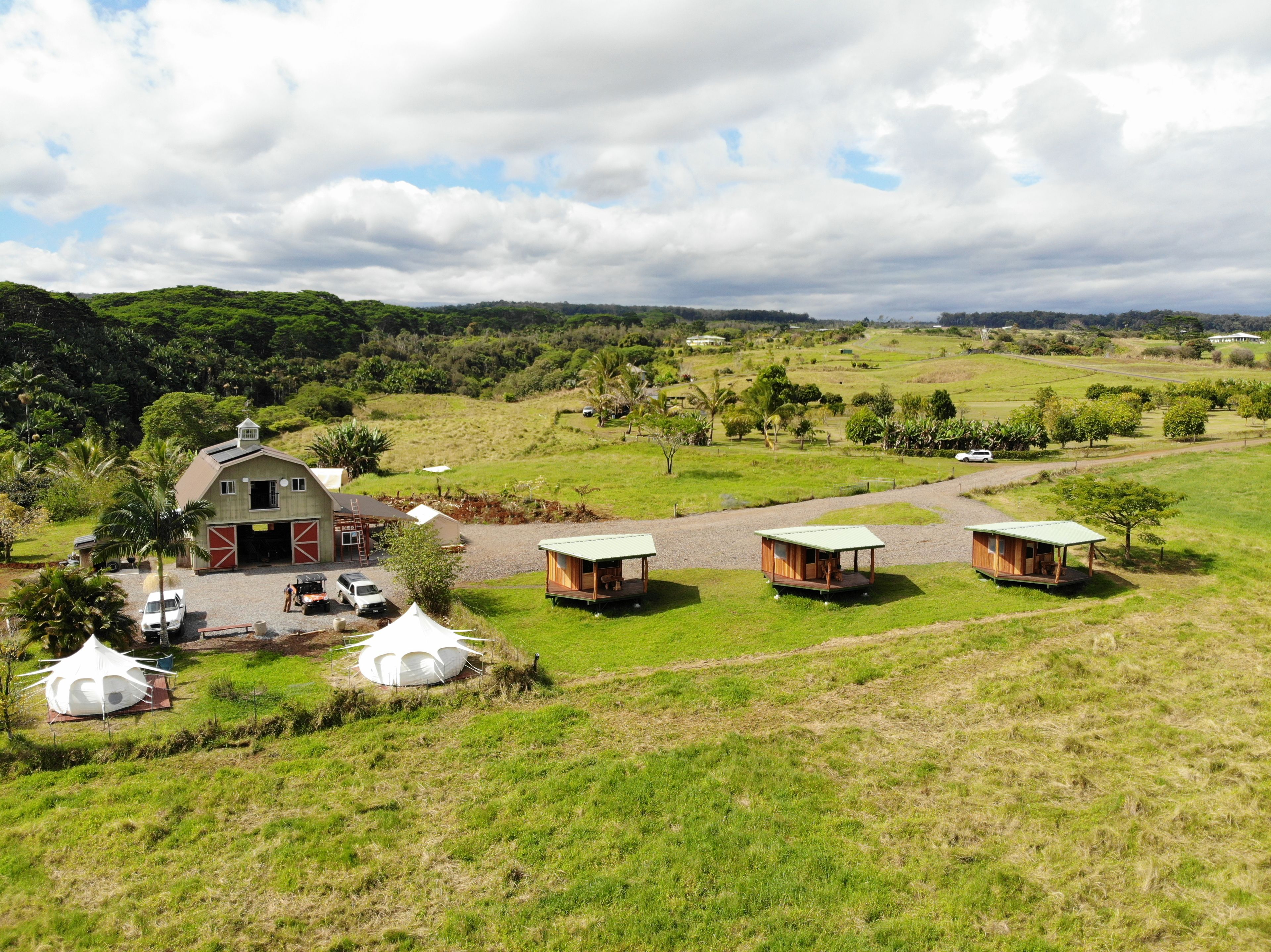 A rural property with a barn, guest cabins, and a gravel driveway.