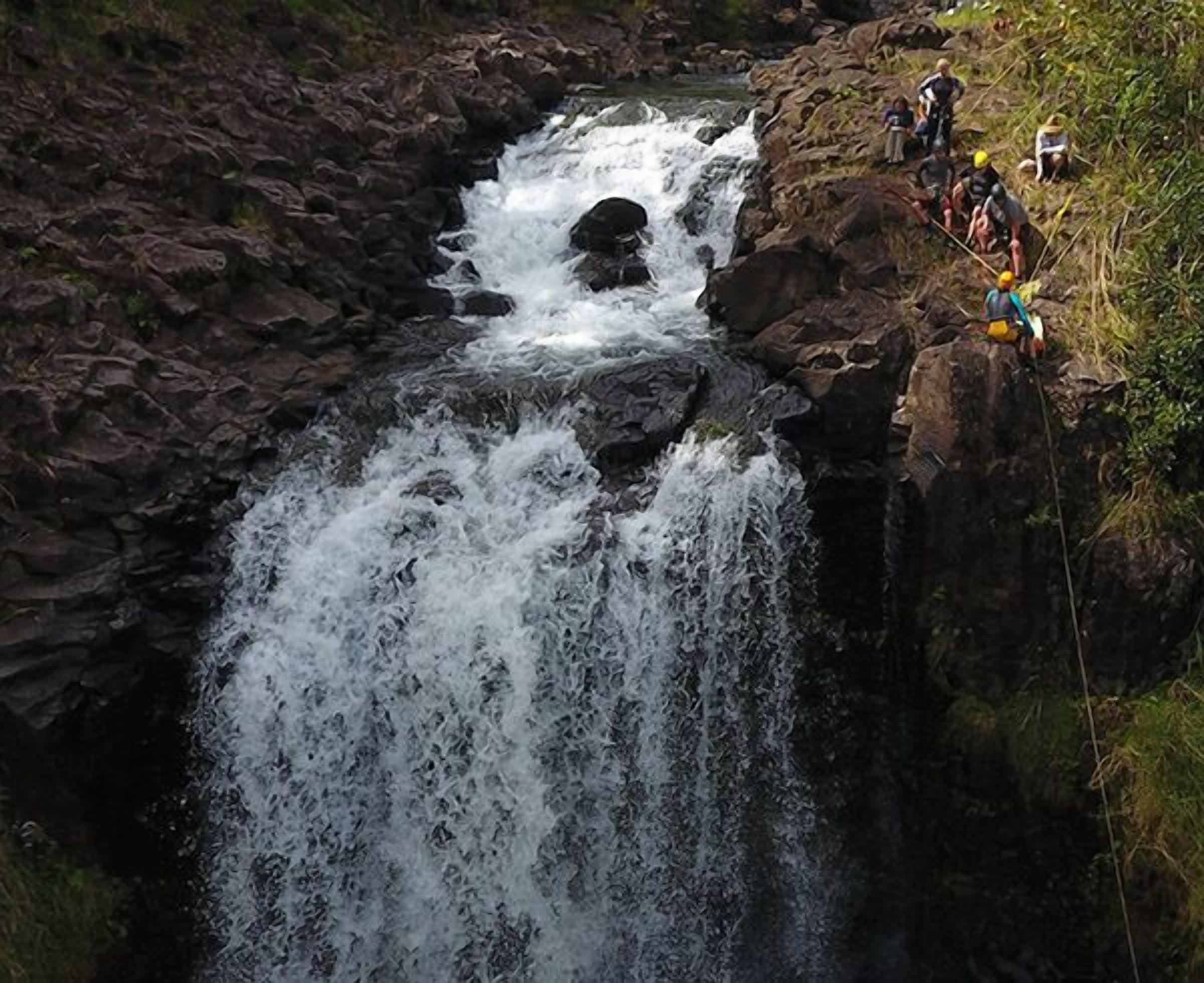 A waterfall cascading over rocks with a group of people observing it.