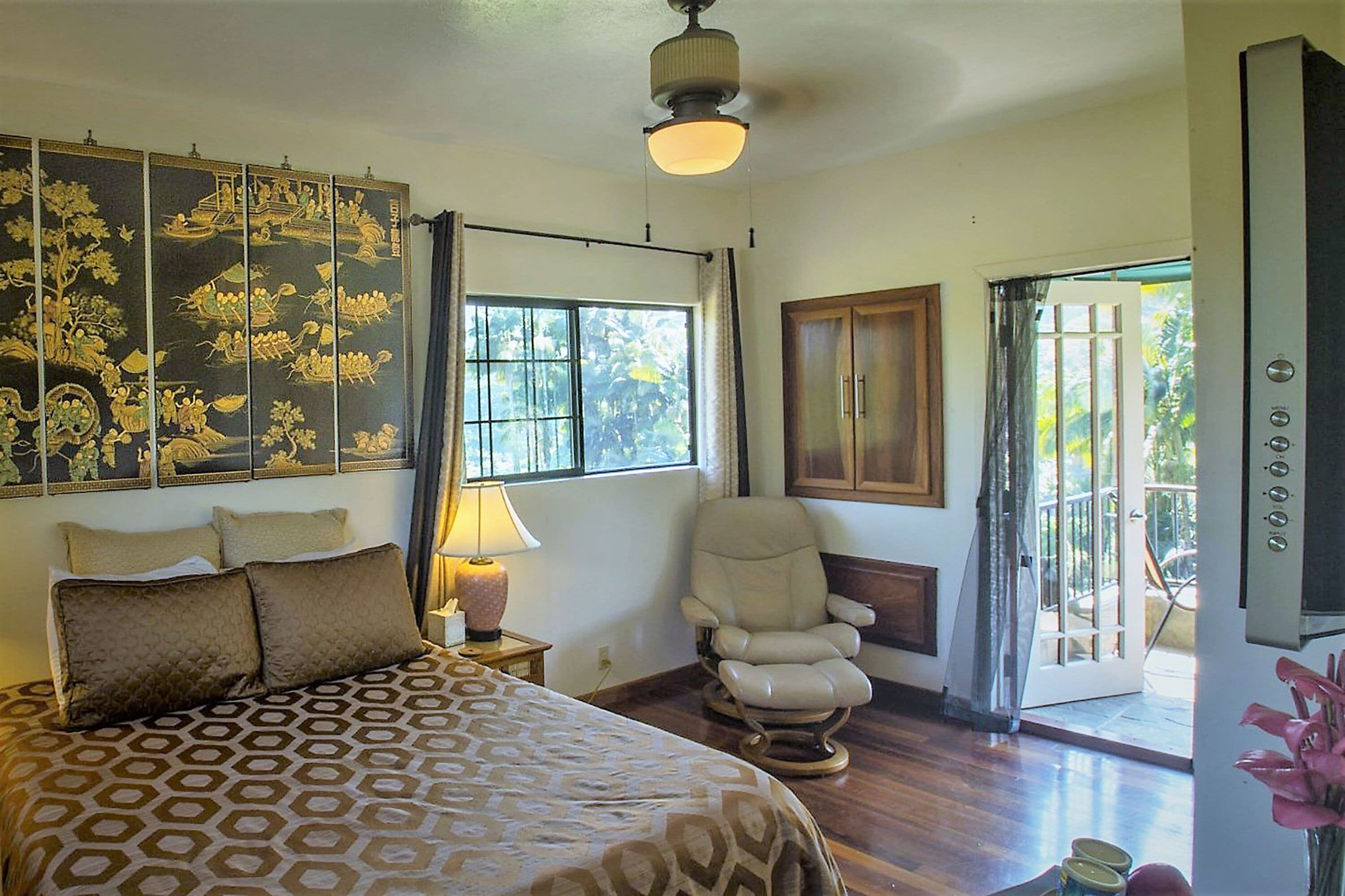 Quarto com cama, cadeira, janela e porta que dá para uma varanda.