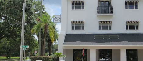 Un bâtiment blanc avec un auvent noir, une enseigne indiquant « Hôtel » et un panneau « Stationnement interdit ».