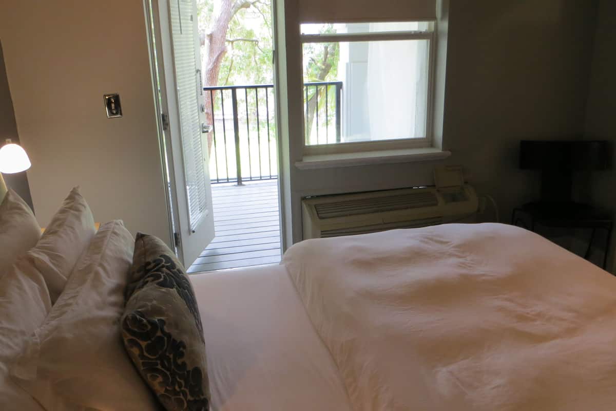 Une chambre d’hôtel avec un lit, une télévision et une fenêtre donnant sur un balcon.
