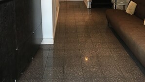Une salle d’attente avec un bureau en bois foncé, une orchidée en pot et un ordinateur portable. Un escalier mène à un autre étage.