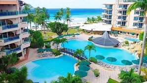 Un resort con varias piscinas, una playa y vistas al océano.