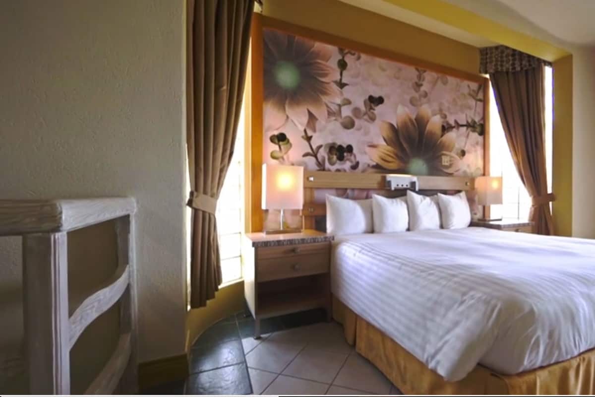 Ein Hotelzimmer mit einem großen Bett, zwei Nachttischen und einem blumigen Kopfstück.
