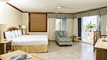 Habitación de hotel con cama, una silla, un escritorio y un balcón con vistas.