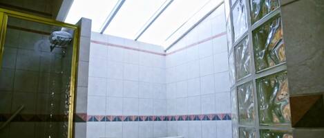 A bathroom with a glass shower enclosure, a bathtub, and tiled walls with a decorative border.