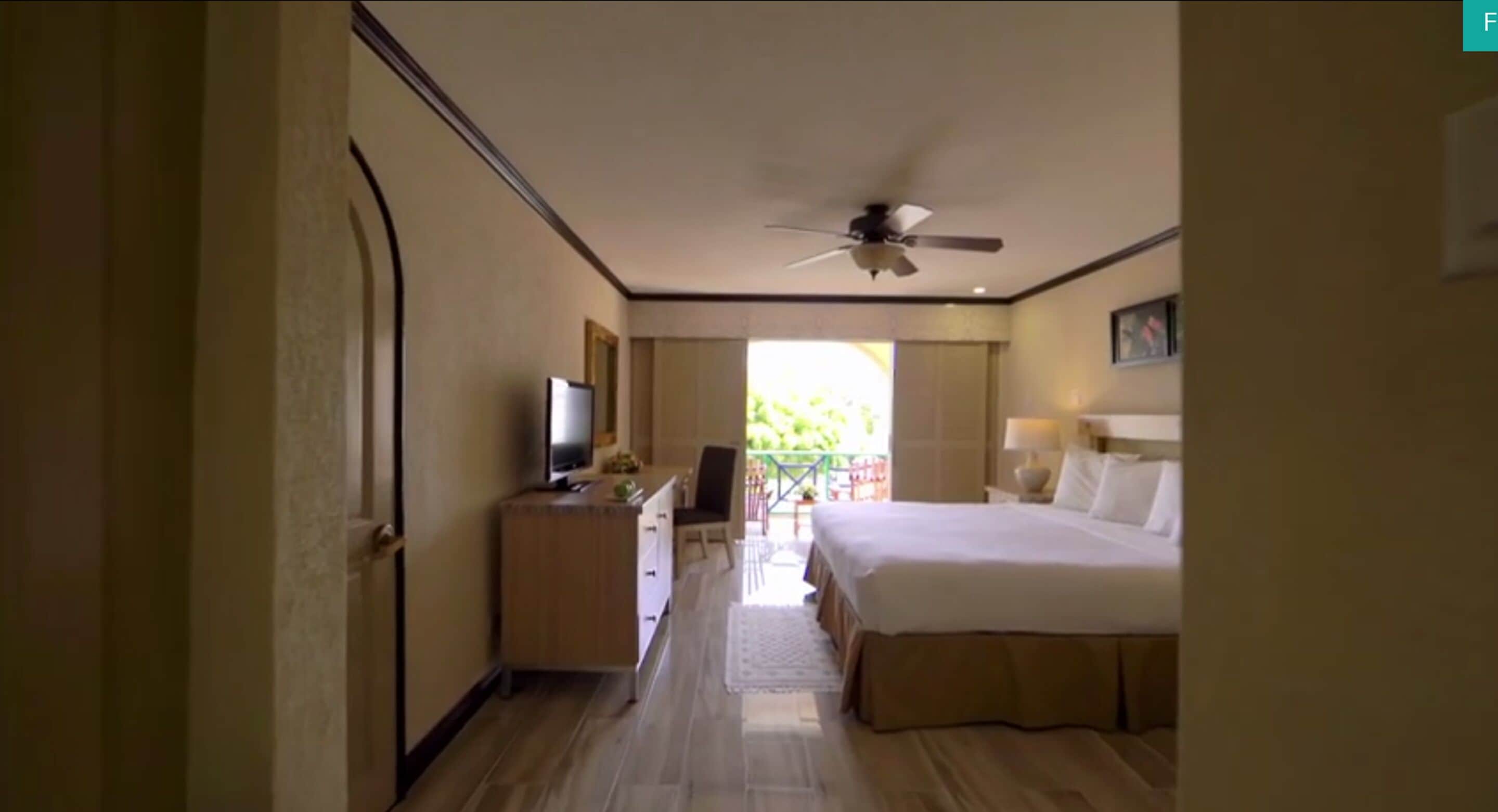 Una habitación de hotel con cama, televisor, escritorio y vistas al exterior.