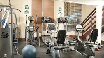Een fitnessruimte met diverse trainingsapparaten, waaronder loopbanden, elliptische trainers en een Cybex gewichtmachine.
