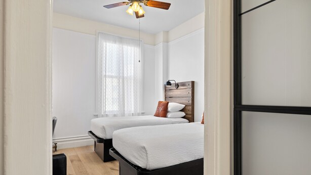 A bedroom with two beds, a ceiling fan, and a window with sheer curtains. - The Andrews Hotel (San Francisco)