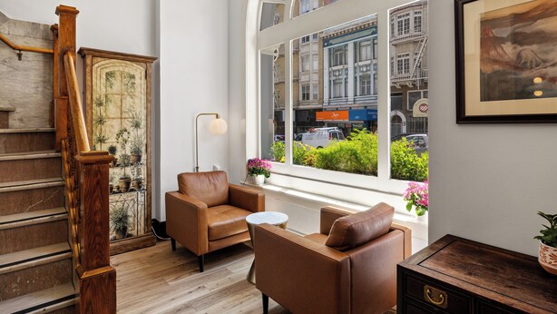 Ein modernes Interieur mit Treppe, Ledersesseln, einem kleinen Tisch und einem großen Fenster mit Blick auf die Stadt.