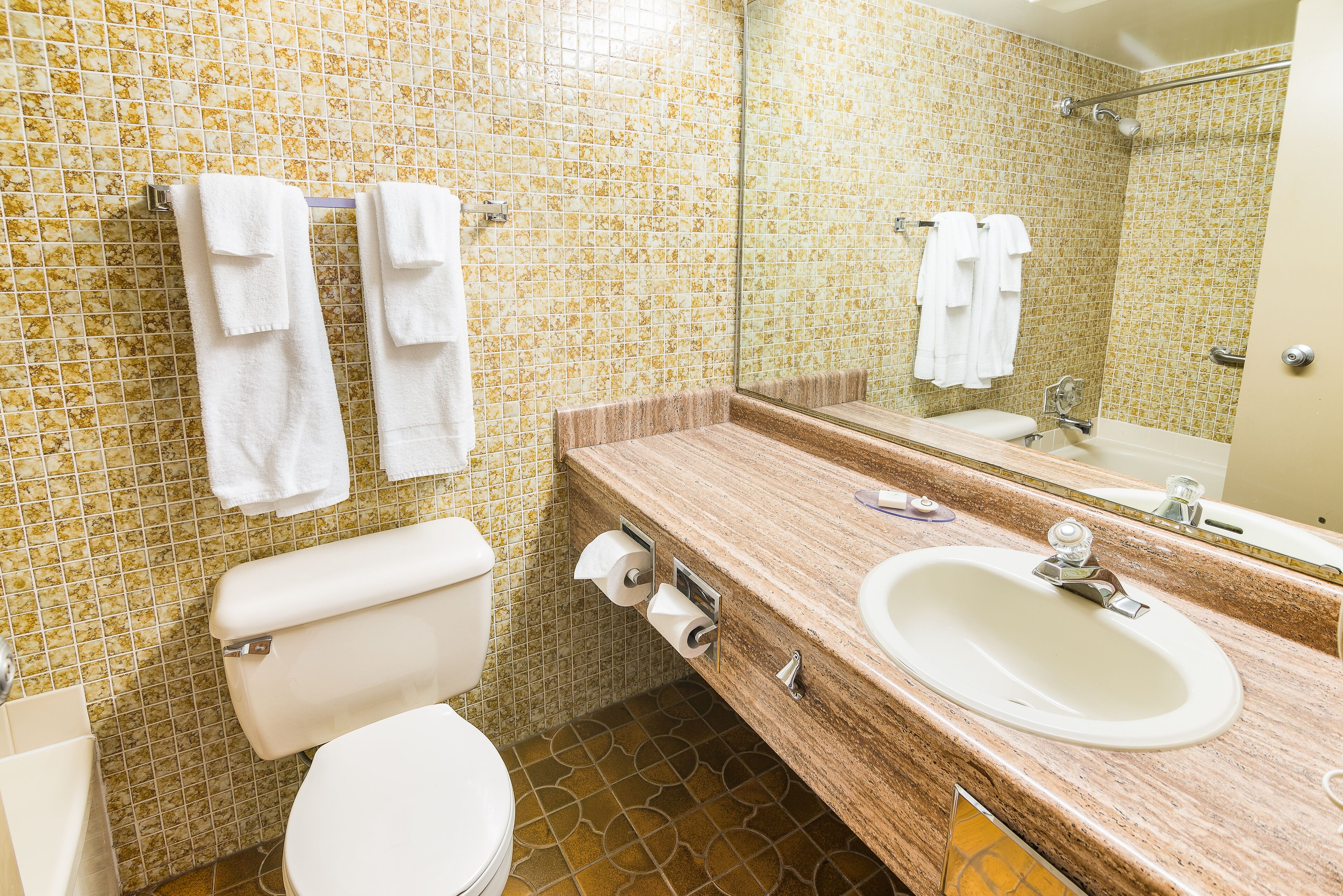 A bathroom with a toilet, sink, and mirror.