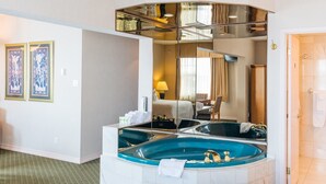 A hotel bathroom with a large bathtub, a mirror, and a shower area.