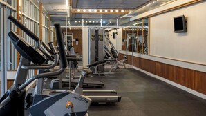A gym with cardio machines, weight equipment, and mirrors on the walls.