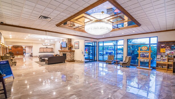 A spacious lobby with a chandelier, a reception desk, and a view of the outside.