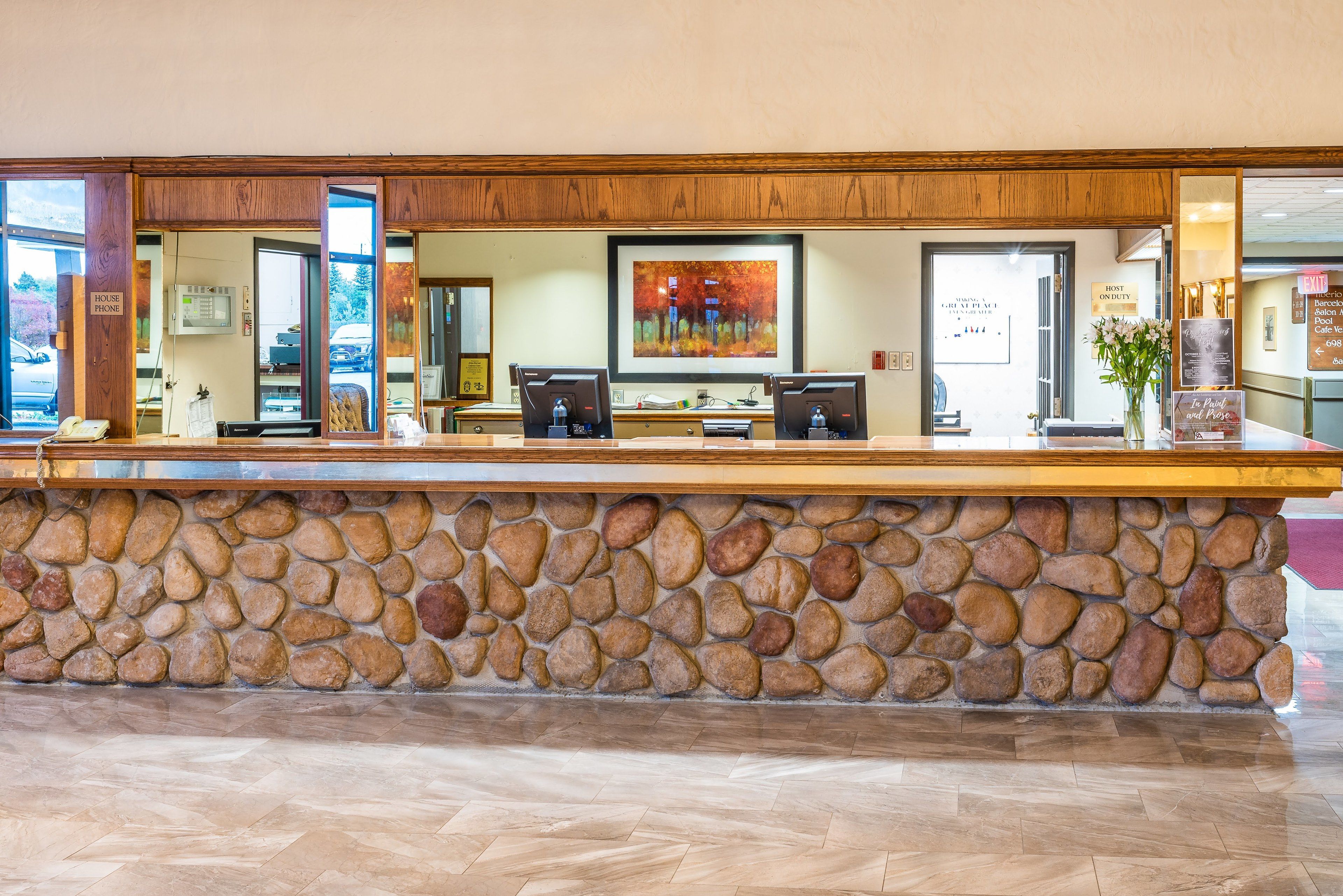 A reception desk with a stone wall, two computer monitors, and a framed picture on the wall.