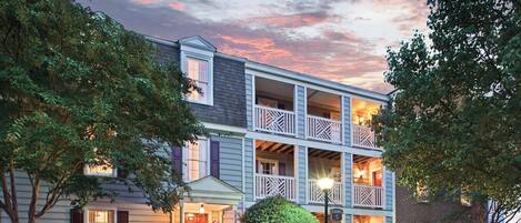 A multi-story building with a balcony on the second floor, a covered front porch, and a brick facade.