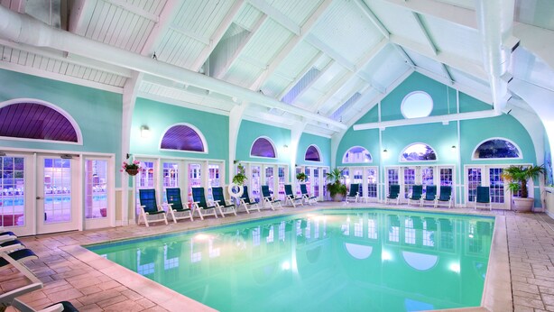 An indoor swimming pool with multiple lounge chairs and arched doorways. - Club Wyndham Kingsgate (Williamsburg)