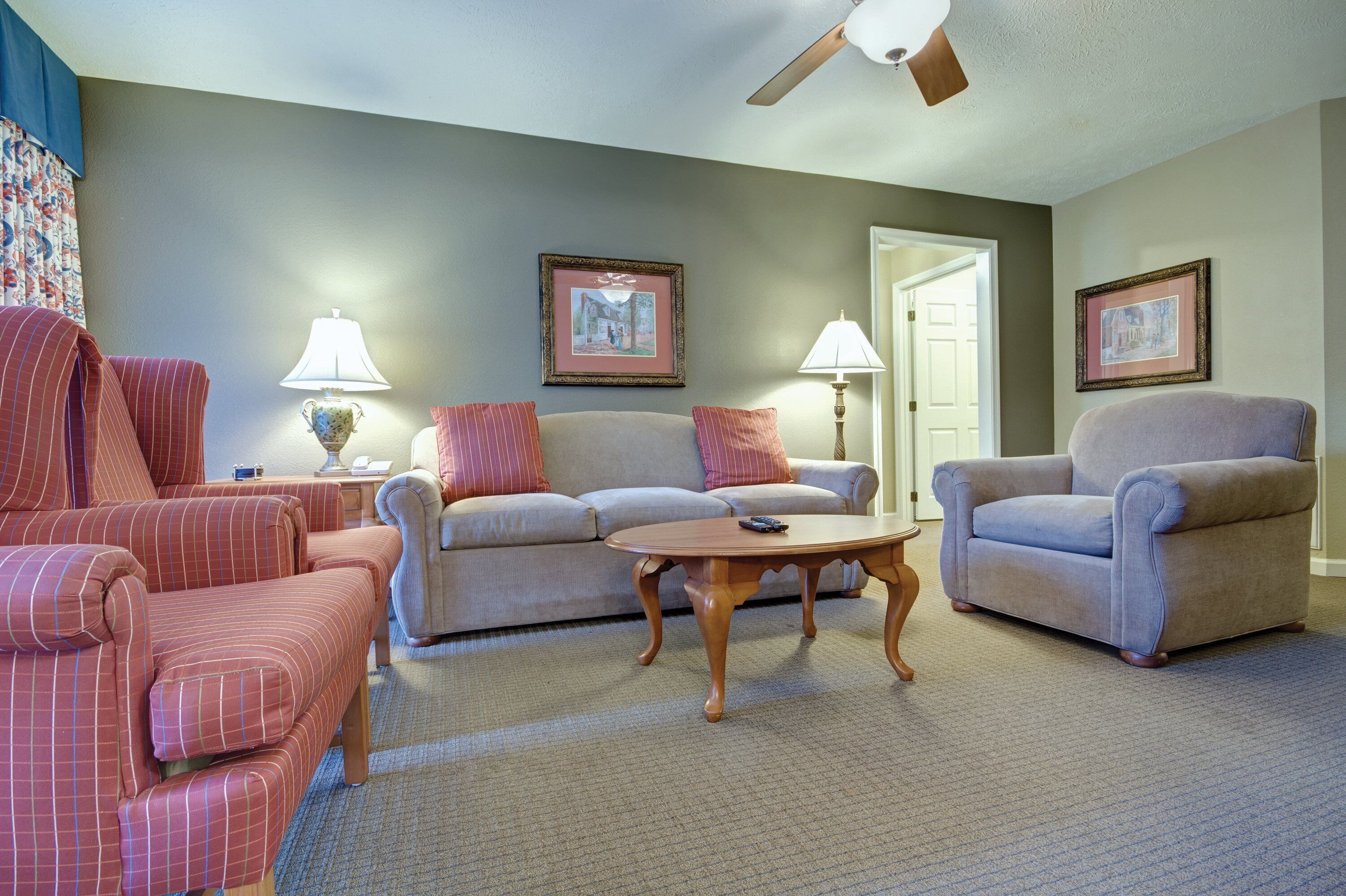 A living room with a sofa, two armchairs, a coffee table, and two lamps.