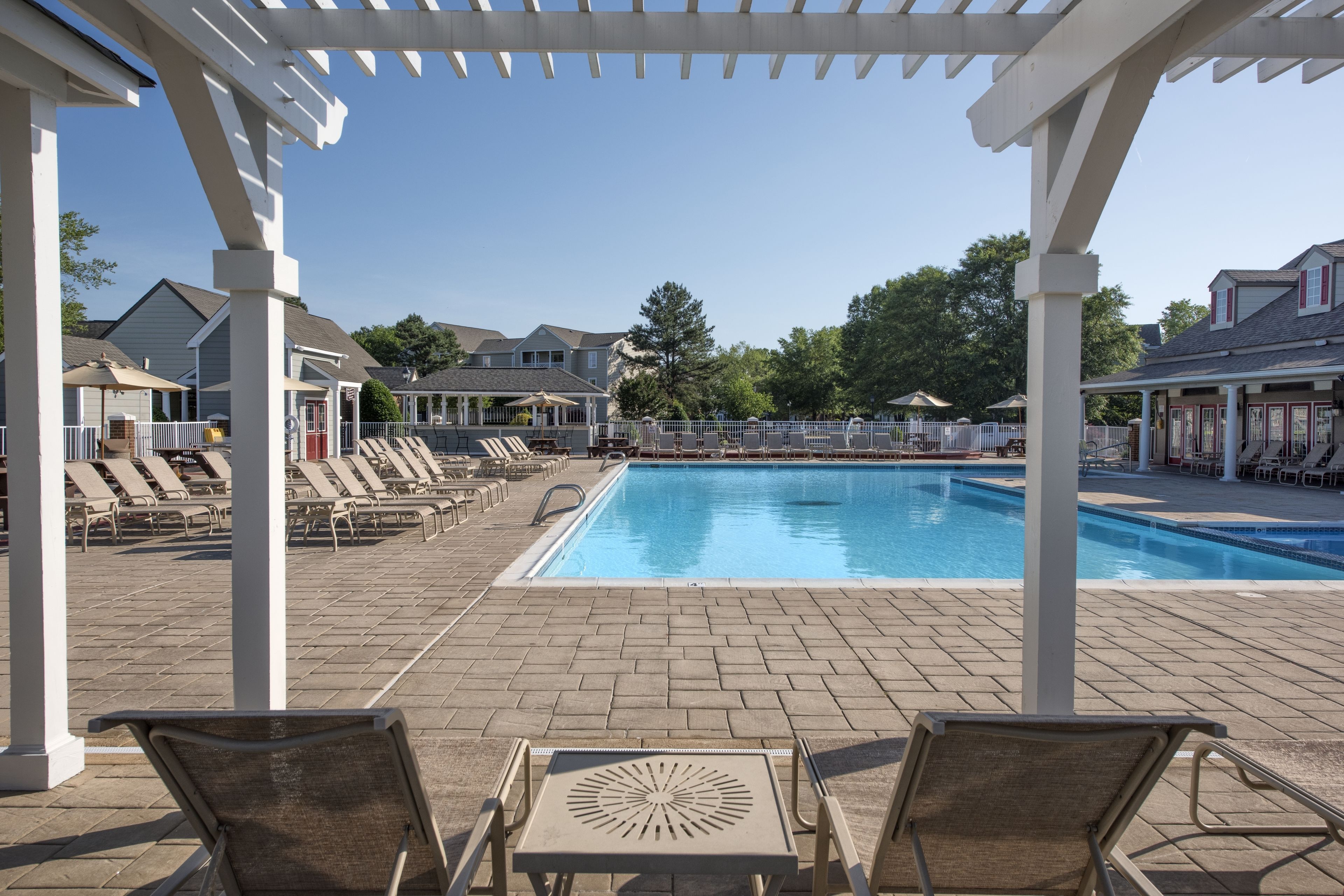 A pool area with lounge chairs and umbrellas, surrounded by a covered walkway.