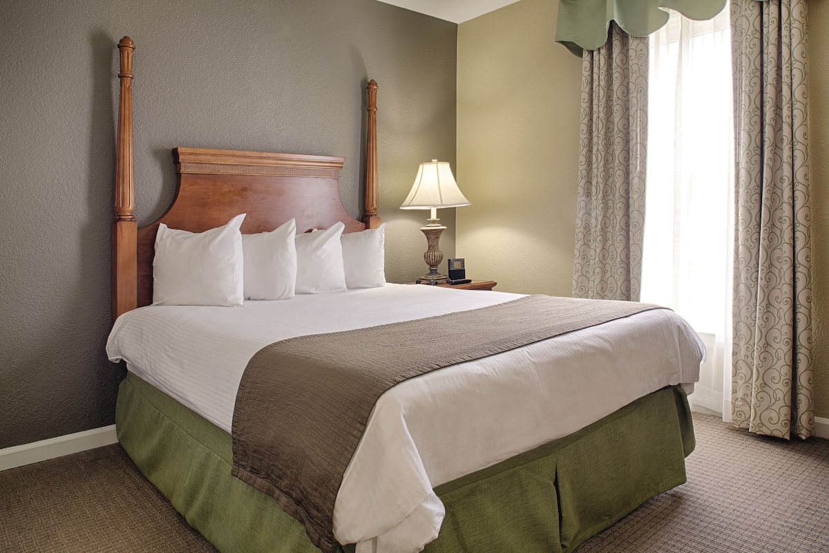 A neatly made bed with a wooden headboard, white pillows, and a brown blanket.