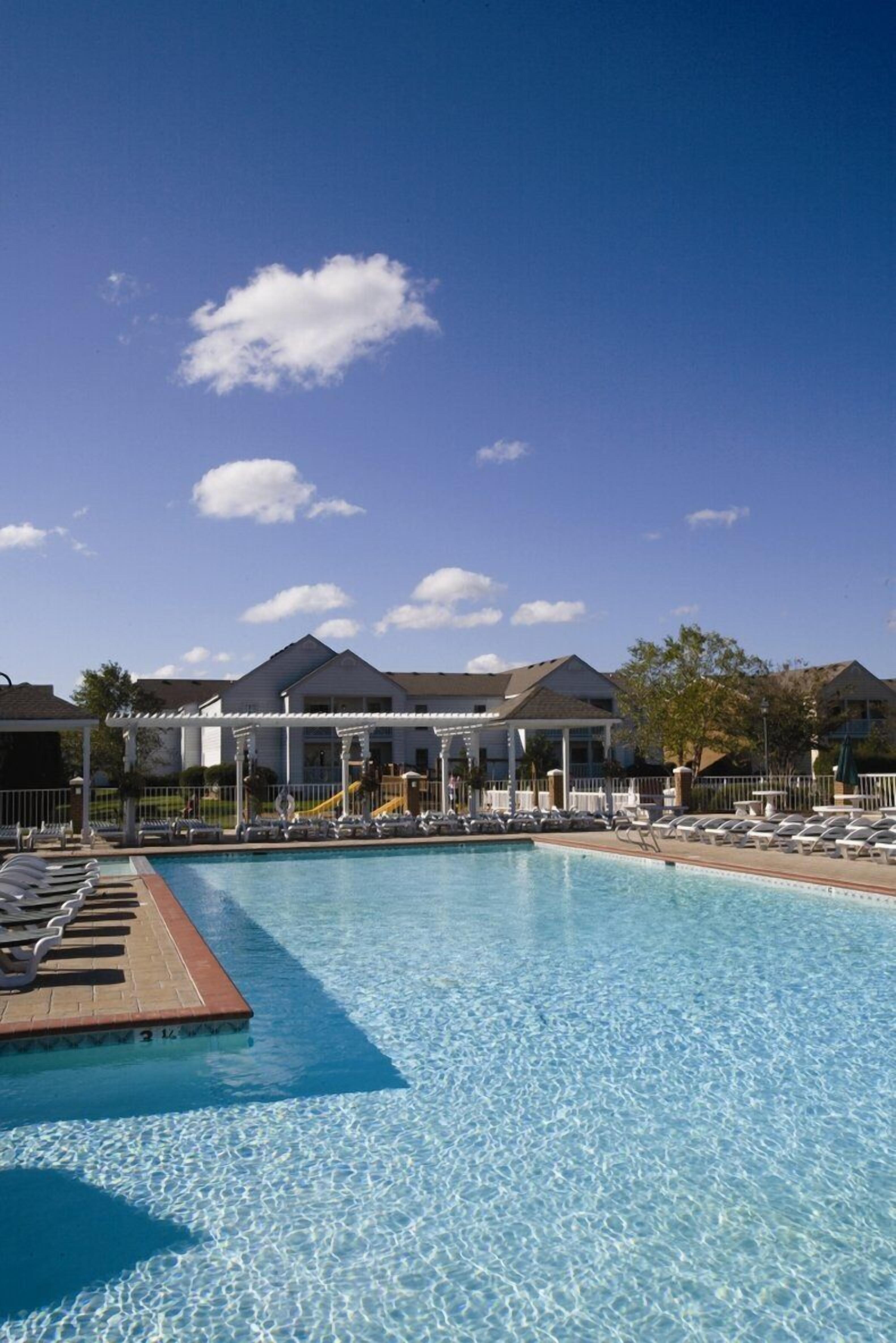 A clear blue pool with lounge chairs and a covered pavilion.