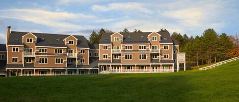 A multi-story residential building with a flat roof, multiple balconies, and a covered front porch.
