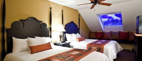 A hotel room with two beds, a ceiling fan, a TV, and a window with a view of a snowy landscape.
