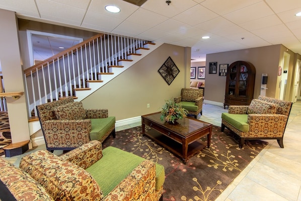 A spacious living area with patterned sofas, a coffee table, and a staircase leading to another level.