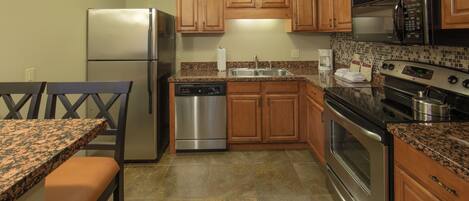A kitchen with wooden cabinets, stainless steel appliances, granite countertops, and a tiled backsplash.
