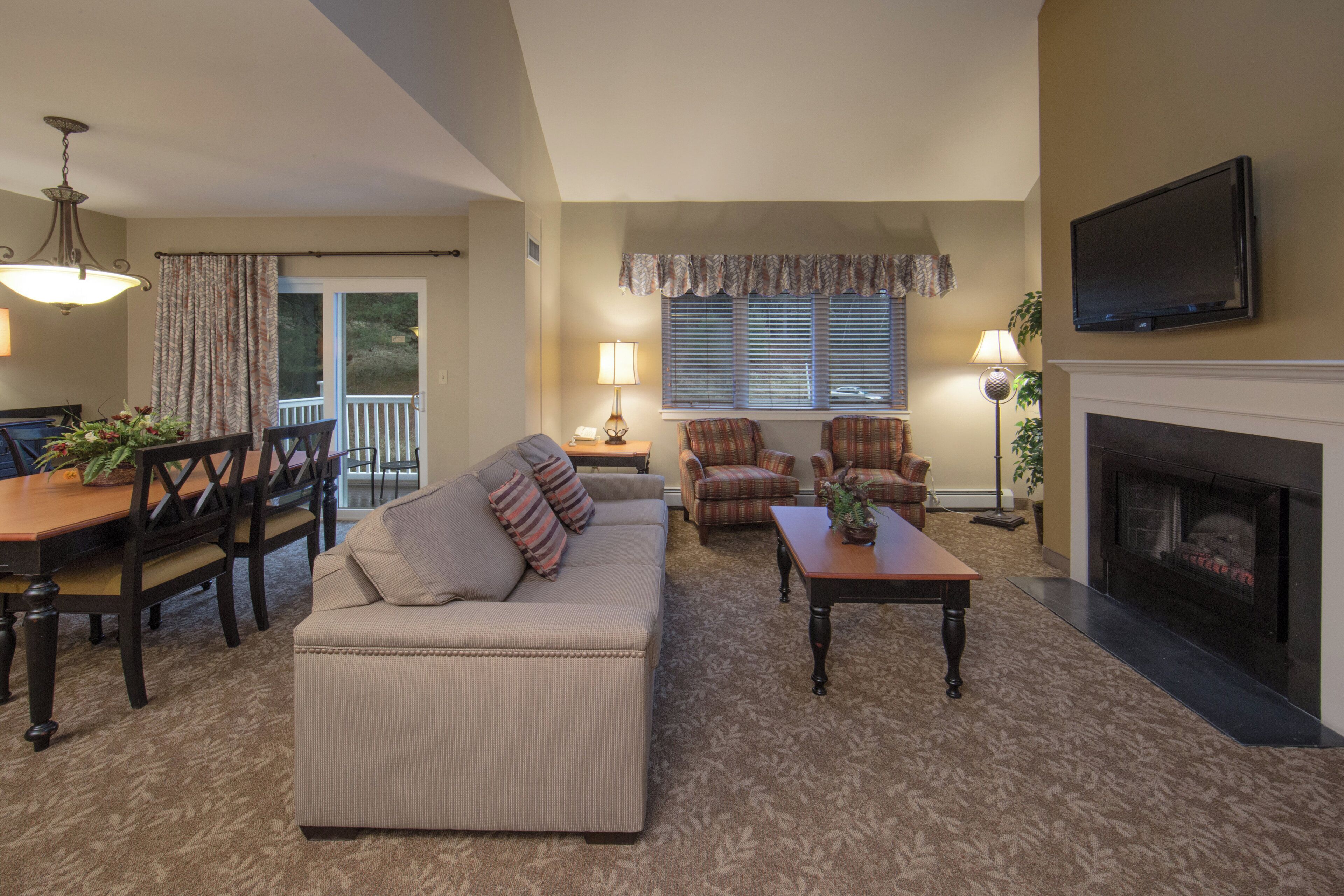 A living room with a sofa, armchairs, a dining table, and a fireplace.