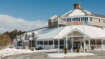 A hotel with a covered entrance, multiple flags, and a snow-covered roof.