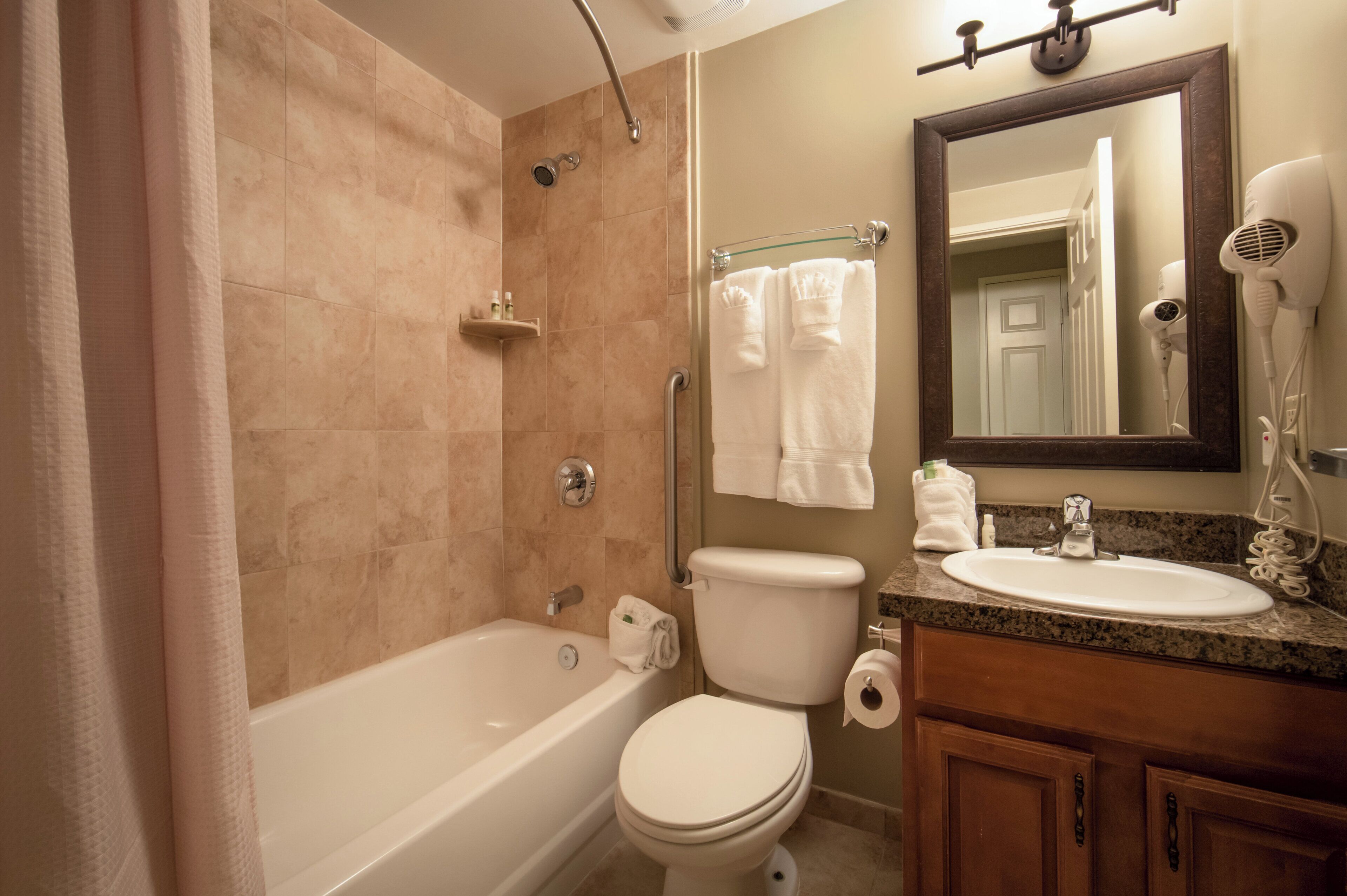 Un baño con bañera, inodoro, lavamanos y espejo.