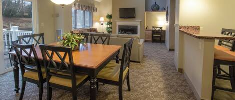 A dining area with a table and chairs, a fireplace, and a television in the background.