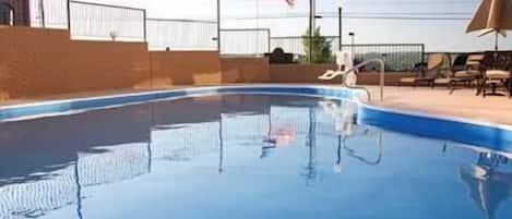 A swimming pool with a brick wall and a metal fence.